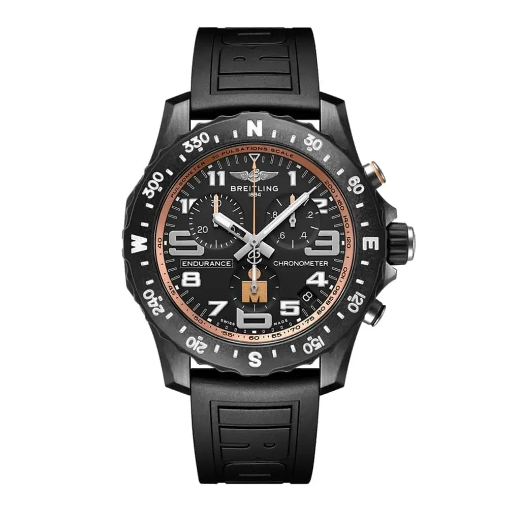 A Breitling Endurance series chronograph watch featuring a black ceramic case and rubber strap, with a black dial accented by orange details. The bezel includes cardinal direction markings (N, E, S, W), and the watch is equipped with a three-register chronograph, tachymeter, and pulsometer scales, designed for durability and performance in sports and adventure settings.
